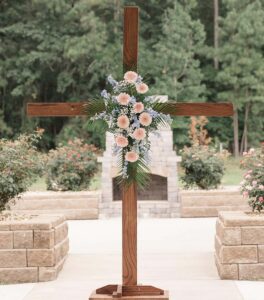 Christian cross with flowers pinned to it.