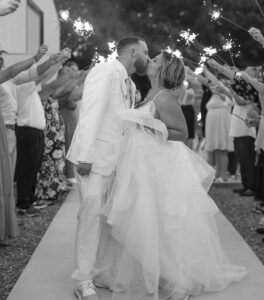 Couple kissing at wedding reception in black and white image.