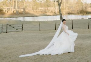 Bride standing in pasture with long train