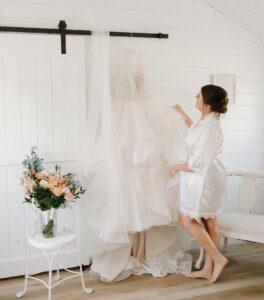 Bride in robe looking over dress