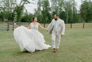 Bride and groom walking through pasture